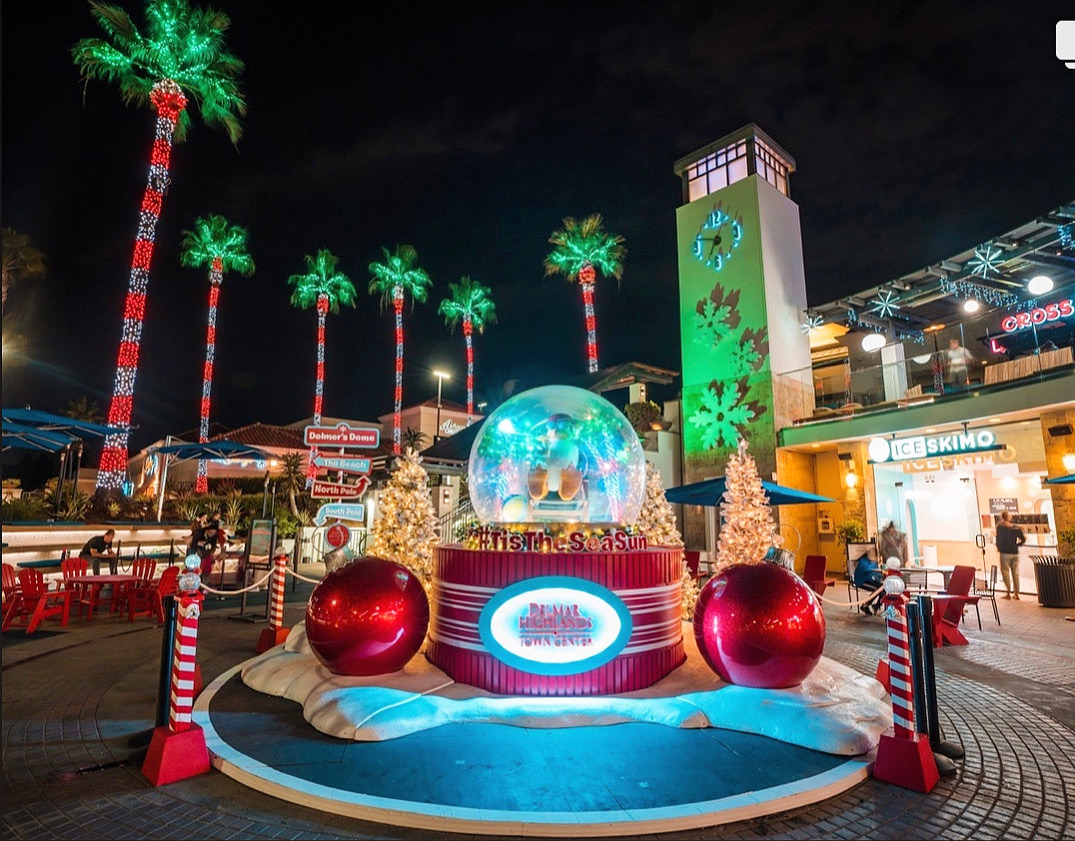 Large holiday display with illuminated palm trees and a snow globe at Del Mar Highlands